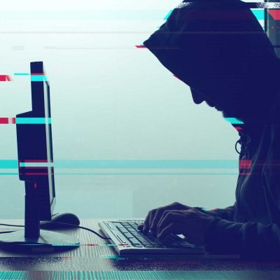 Hacker at computer creating phishing email