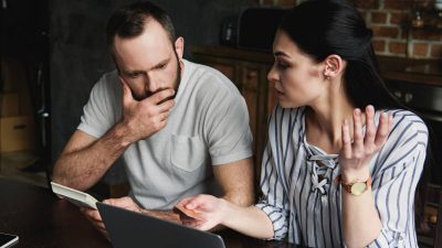 Man watching woman work on laptop